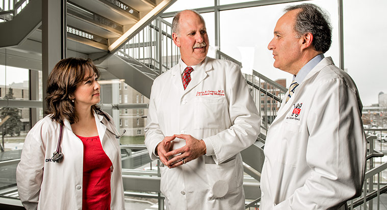 Three medical professionals speaking in a lobby near a staircase